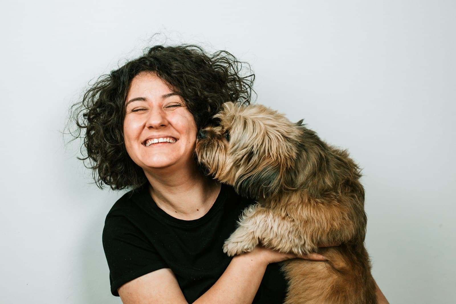 Mujer sonriente abrazando a su perro peludo